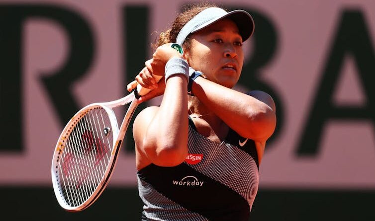 A young woman swings a tennis racket.