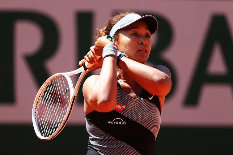 A young woman swings a tennis racket.